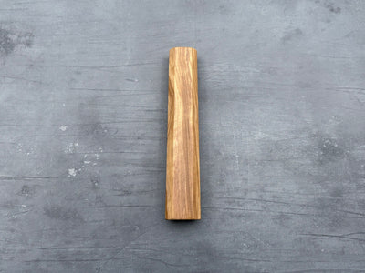 A single piece of olive wood with an octagonal shape handle for a kitchen knife.