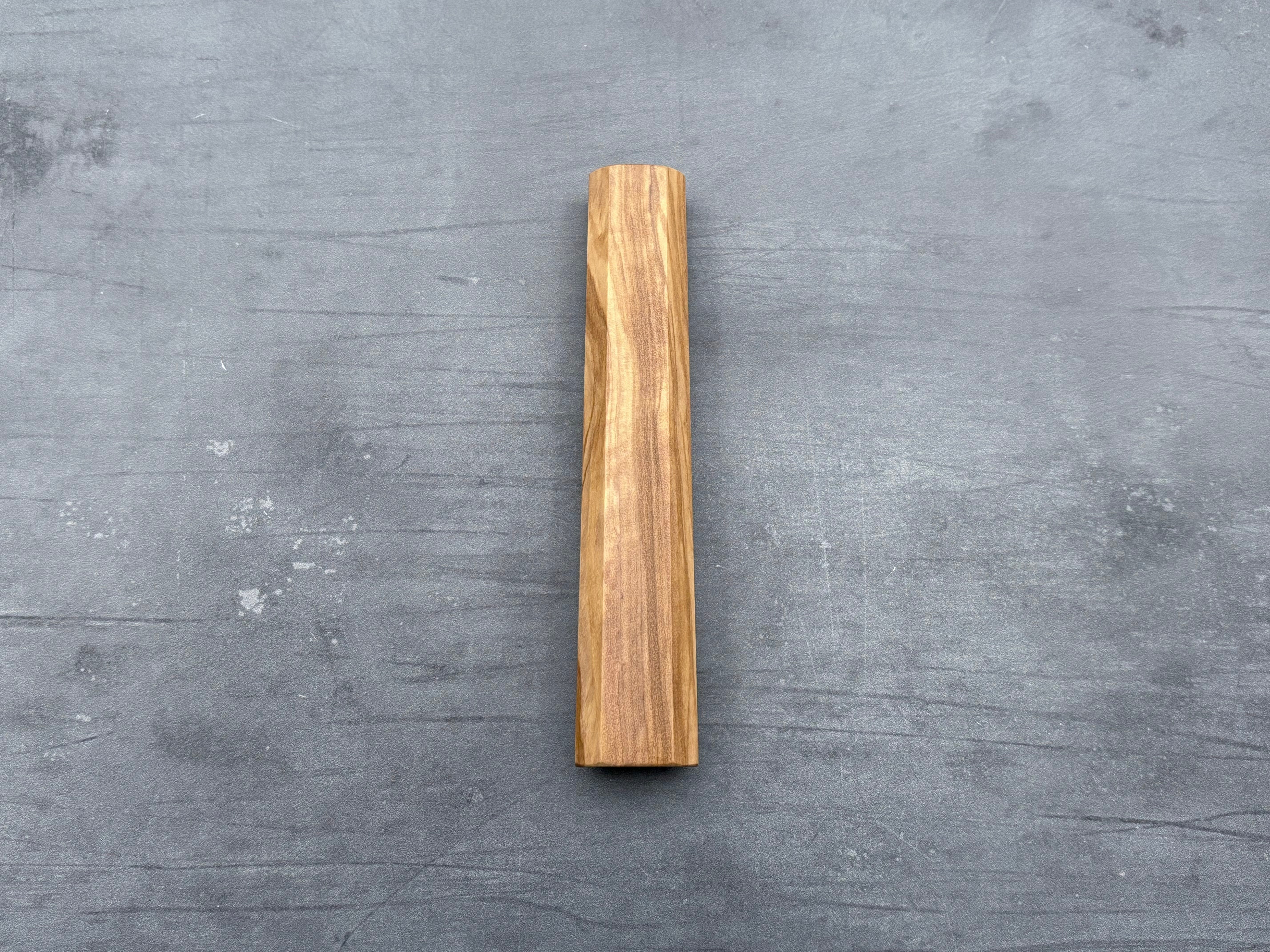 A single piece of olive wood with an octagonal shape handle for a kitchen knife.